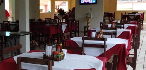 uma fila de mesas num restaurante com toalha de mesa vermelha e branca em Hotel Gruta da Serra em Guaramiranga