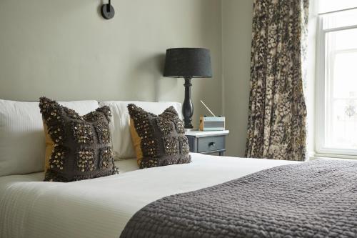 a bedroom with a bed with pillows and a window at The King's Arms in Dorchester
