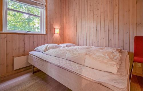 Nice Home In Ebeltoft With Kitchen في Øksenmølle: سرير في غرفة خشبية مع نافذة