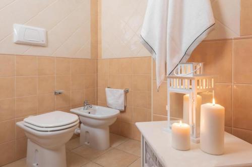 a bathroom with a toilet and a sink and two candles at Stylish Residence Le Fontane no2503 in Villasimius
