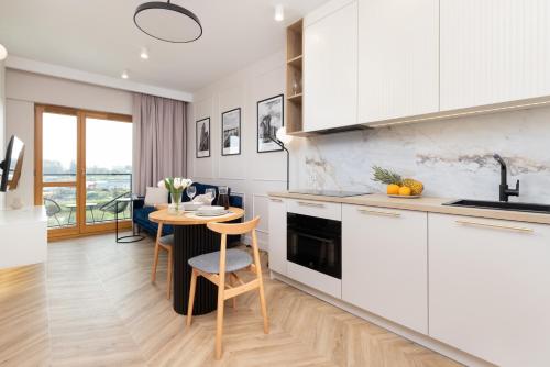 a kitchen with white cabinets and a table with chairs at Sienna Grobla Apartment View of the Motława by Renters in Gdańsk