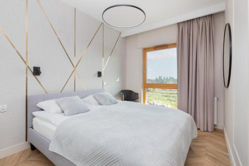 a bedroom with a large white bed and a window at Sienna Grobla Apartment View of the Motława by Renters in Gdańsk