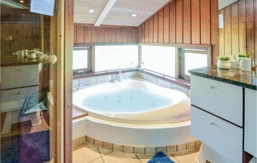 a large bath tub in a bathroom with wooden walls at Awesome Home In Ebeltoft With 3 Bedrooms, Sauna And Wifi in Ebeltoft