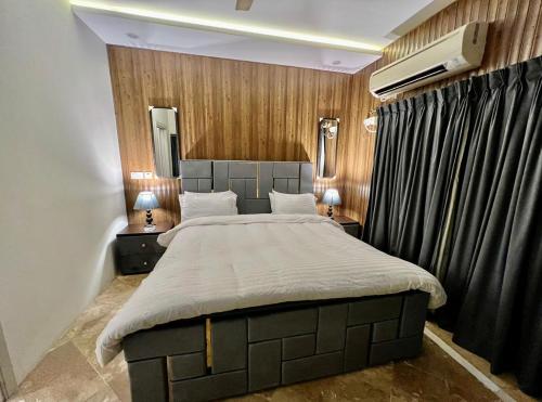 a bedroom with a large bed with two tables and two lamps at Homtel Signature Suites in Islamabad