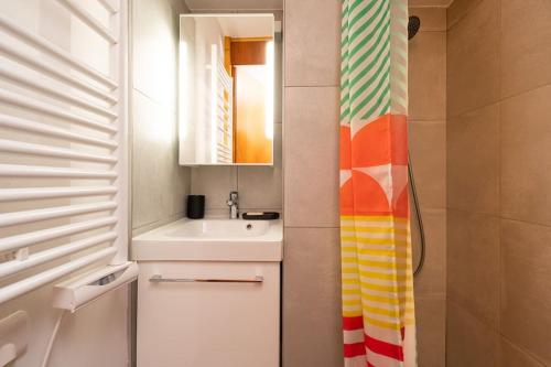a bathroom with a sink and a shower curtain at L'Arc-en-Ciel - Appartement sur les hauteurs du Mottaret avec accès aux pistes in Les Allues