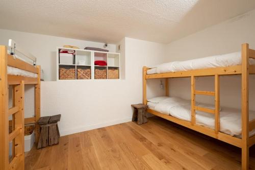 a room with two bunk beds and a wooden floor at L'Arc-en-Ciel - Appartement sur les hauteurs du Mottaret avec accès aux pistes in Les Allues