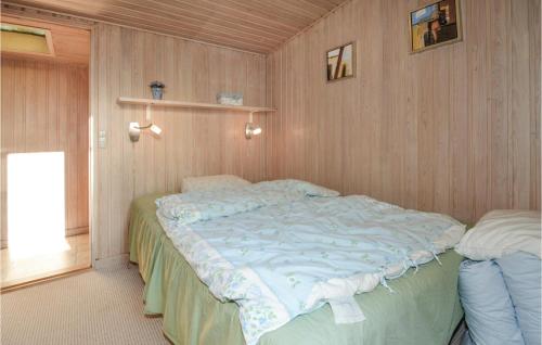 1 dormitorio con 1 cama grande en una pared de madera en Jydehuset, en Slettestrand