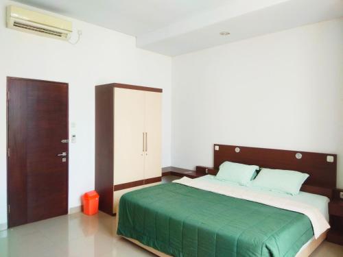 a bedroom with a large bed with a green blanket at Omah Dixy Family Homestay by FH Stay in Bantul