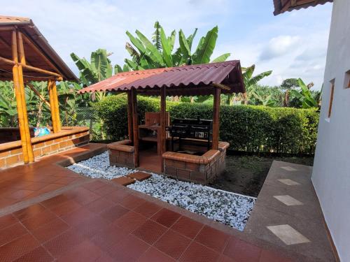 a wooden gazebo with a bench in a yard at Chalet la texana in Filandia