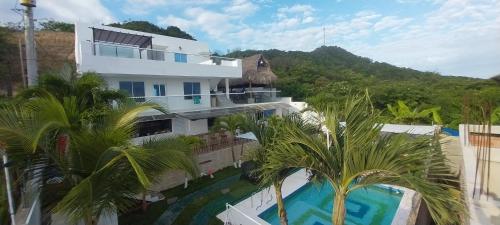 a building with a swimming pool and palm trees at Cabaña villa kary in Barranquilla