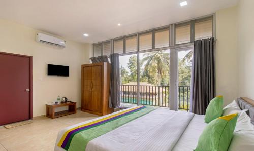 a bedroom with a bed and a large window at Treebo The Rove, Coorg in Madikeri