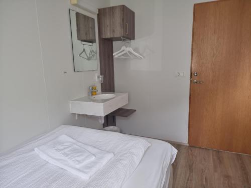 Litla-Hof Guesthouse في هوف: غرفة نوم بيضاء مع سرير ومغسلة