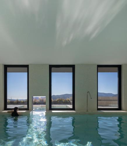 a person sitting in a swimming pool with windows at Casa de São Lourenço - Burel Panorama Hotel - member of Design Hotels in Manteigas