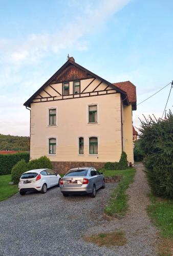 two cars parked in front of a large house at Apartmán Nad hradem in Týnec nad Sázavou