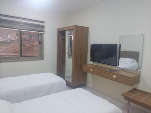 um quarto com 2 camas e uma televisão de ecrã plano em Albasha em Wadi Musa