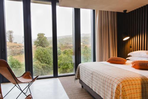 a hotel room with a bed and large windows at TerraSense Mountain Charm Retreat & Farm in Videmonte