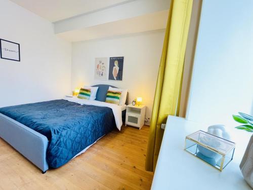 a bedroom with a bed with a blue blanket at aday - Sunshine apartment in the heart og Hjorring in Hjørring
