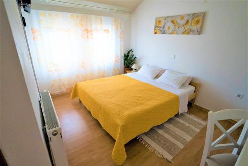 a bedroom with a bed with a yellow blanket and a window at Kmetija Podobnik in Idrija