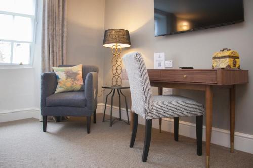 a room with a desk and two chairs and a lamp at The King's Arms in Dorchester