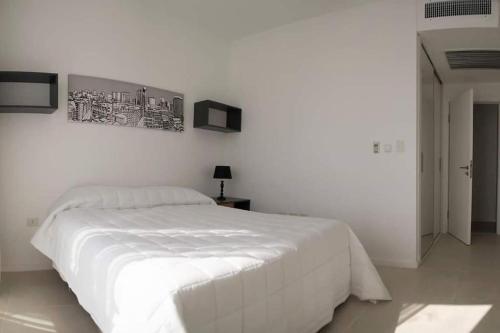 アスンシオンにある706 - The Tower Luxury 2 Bedroomの白いベッドと壁の絵が備わる白いベッドルーム1室