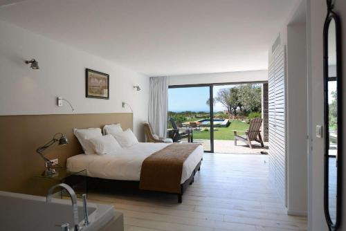 Un dormitorio con una cama y un baño con bañera. en Les lofts de palombaggia, en Porto Vecchio