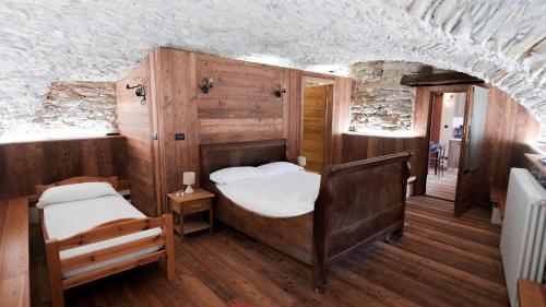 a bedroom with two beds in a room with wooden walls at La Mizoùn de Marguerito - Appartamento Genziana in Chiappera