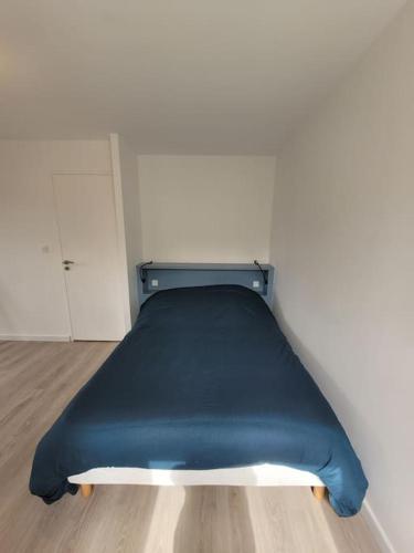 a blue bed in a room with a white wall at Maison familiale proche plages avec jacuzzi in Tréflez