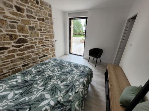 a bedroom with a bed and a brick wall at Maison familiale proche plages avec jacuzzi in Tréflez