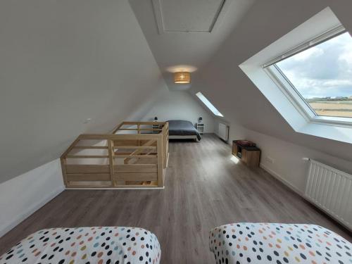 a attic room with a bed and a window at Maison familiale proche plages avec jacuzzi in Tréflez
