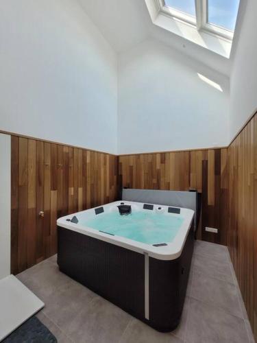a large bath tub in a room with wooden walls at Maison familiale proche plages avec jacuzzi in Tréflez