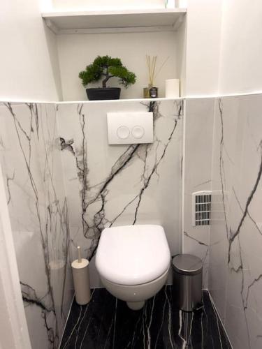 La salle de bains est pourvue de toilettes blanches et de murs en marbre. dans l'établissement Magnifique appartement de 4 chambres 8 personnes max à 20 minutes de Paris, à Antony
