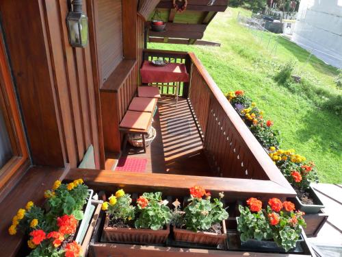 a porch with flowers in pots on a house at Mansarda in chalet a Cortina in Cortina dʼAmpezzo