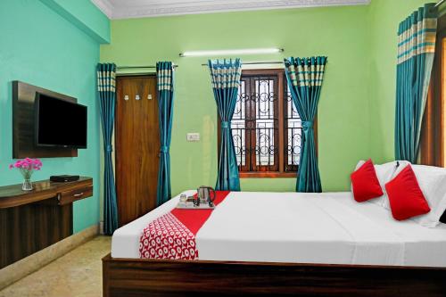um quarto com uma cama com almofadas vermelhas e uma televisão em Flagship Himgiri Guest House em Calcutá