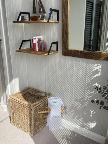 a bathroom with a wicker basket and a mirror at Dewcroft in Horsley