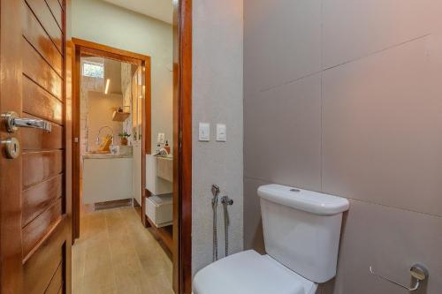 a bathroom with a white toilet and a door at Chalé Alto da Bela Vista por Carpediem in Guaramiranga