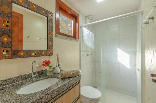 a bathroom with a sink and a toilet and a mirror at Chalé Alto da Bela Vista por Carpediem in Guaramiranga