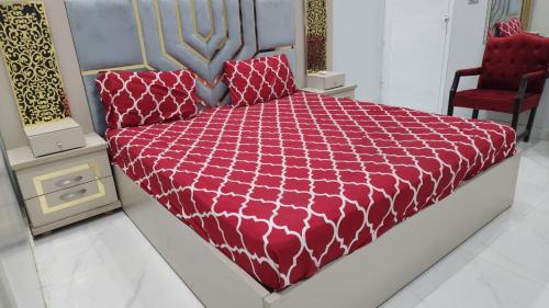 a bedroom with a bed with a red comforter at Hotel Elegant Gulshan-e-Iqbal karachi in Karachi