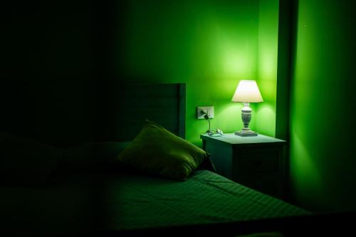 a green room with a bed with a lamp on a night stand at RhelizeOne & Spa جميل in Palermo