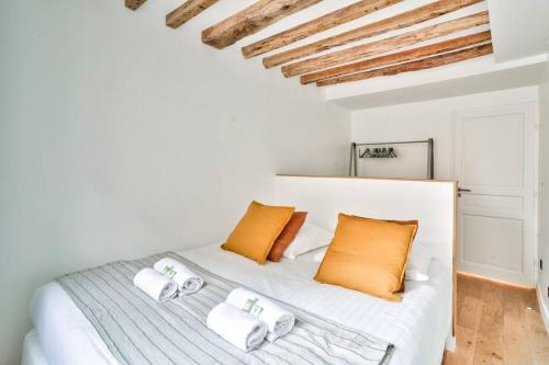 une chambre avec un lit blanc avec des oreillers orange dans l'établissement Magnifique appartement pour 6 - Montorgueil, à Paris