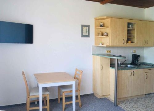 una piccola cucina con un tavolino, un tavolo e sedie di Apartments in Harrachov/Riesengebirge 2300 a Harrachov
