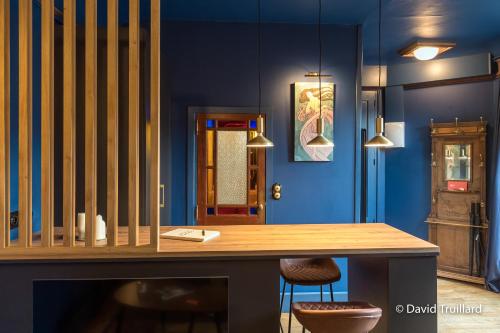 een eetkamer met blauwe muren en een houten tafel bij Suites Mana- Le Boudoir Art Déco 4* Place Ducale Parking inclus in Charleville-Mézières