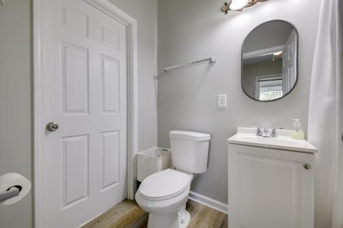 a white bathroom with a toilet and a mirror at Indianapolis Home with Porch - Close to Mile Square! in Indianapolis