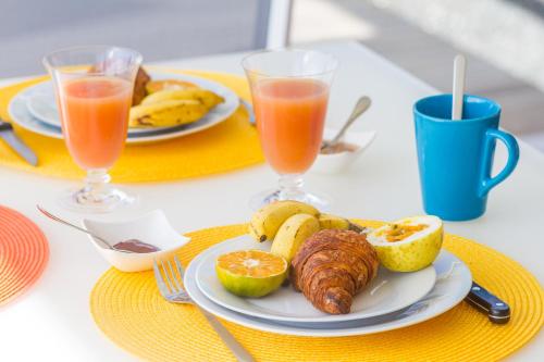 a table with a plate of food and two glasses of orange juice at Iguane House Villas & Micro Spa in Sainte-Anne