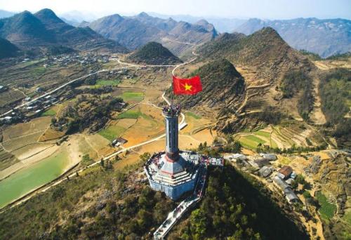 una bandera en la parte superior de un edificio con una montaña en Tour Dong Van stone plateau, en Bản Tùy