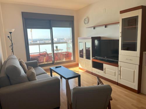 salon z kanapą i telewizorem z płaskim ekranem w obiekcie GATU PREMIUM Marismas, terraza, parking, piscina común y aire acc , " Preferente mayores de 25 años y familias " w mieście El Puerto de Santa María