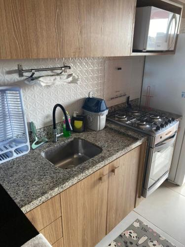 a kitchen with a sink and a stove at Apartamento na Praia do Saco - Condomínio Villa das Águas in Estância