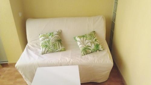 Un sofá blanco con dos almohadas. en Sueña Paco, en Torremolinos