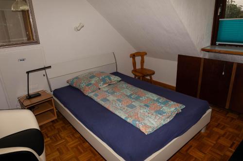 ein kleines Schlafzimmer mit einem Bett und einem Stuhl in der Unterkunft Ferienwohnung bei Stadthagen mit Wlan und Waschmaschine in Niedernwöhren