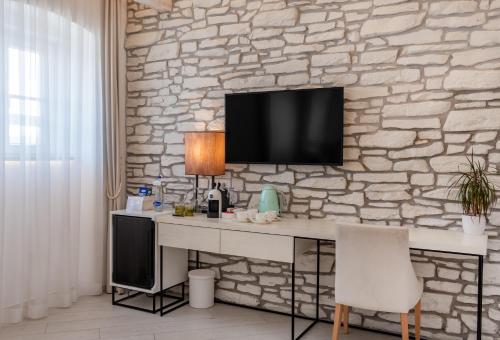 a white desk with a television on a stone wall at Lazure Hotel & Marina in Herceg-Novi