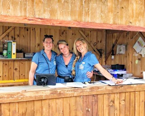 a group of three people standing at a counter at GrandPrixCamp, closest to the Red Bull Ring, up to 4 guests in a tent in Spielberg